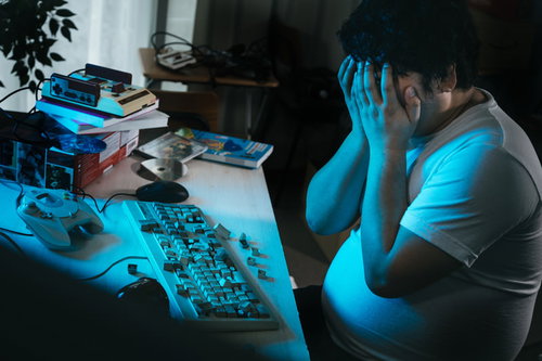 青いLED照明の下で頭を抱える男性