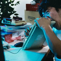 悔しくてキーボードに噛み付く男性の感情表現の写真