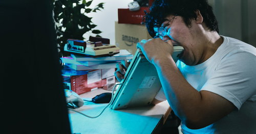 悔しくてキーボードに噛み付く男性の感情表現