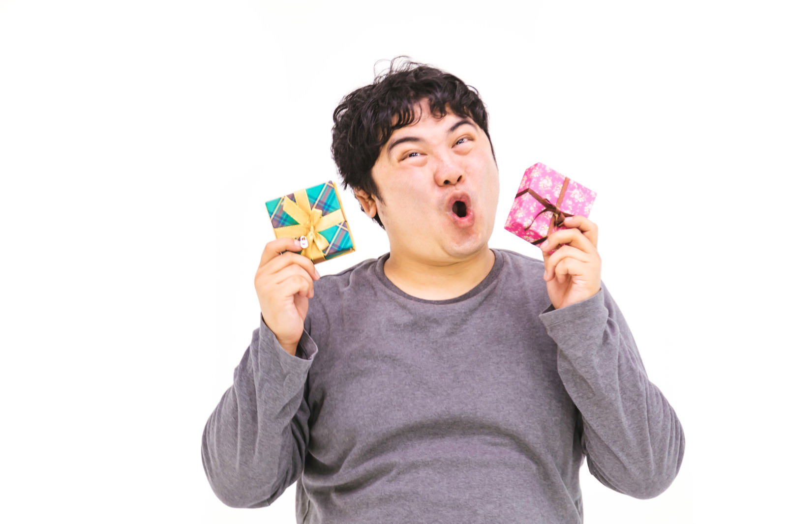 両手にプレゼントを持ち口を大きく開けて喜ぶ男性［モデル：段田隼人］