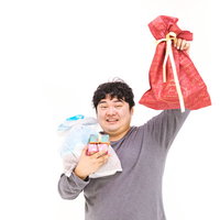 これからプレゼント交換やりますーと赤いリボン袋を掲げる男性の写真