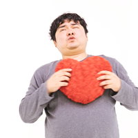 一目惚れでハートにずっきゅん、赤いハート型クッションを抱える男性の写真