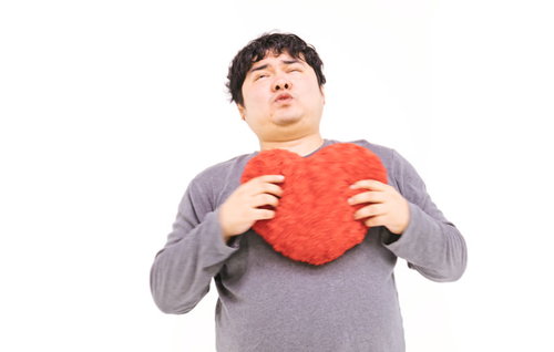 一目惚れでハートにずっきゅん、赤いハート型クッションを抱える男性