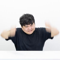 黒Tシャツの男性が両腕を振り上げて怒りの表情を見せる瞬間の写真