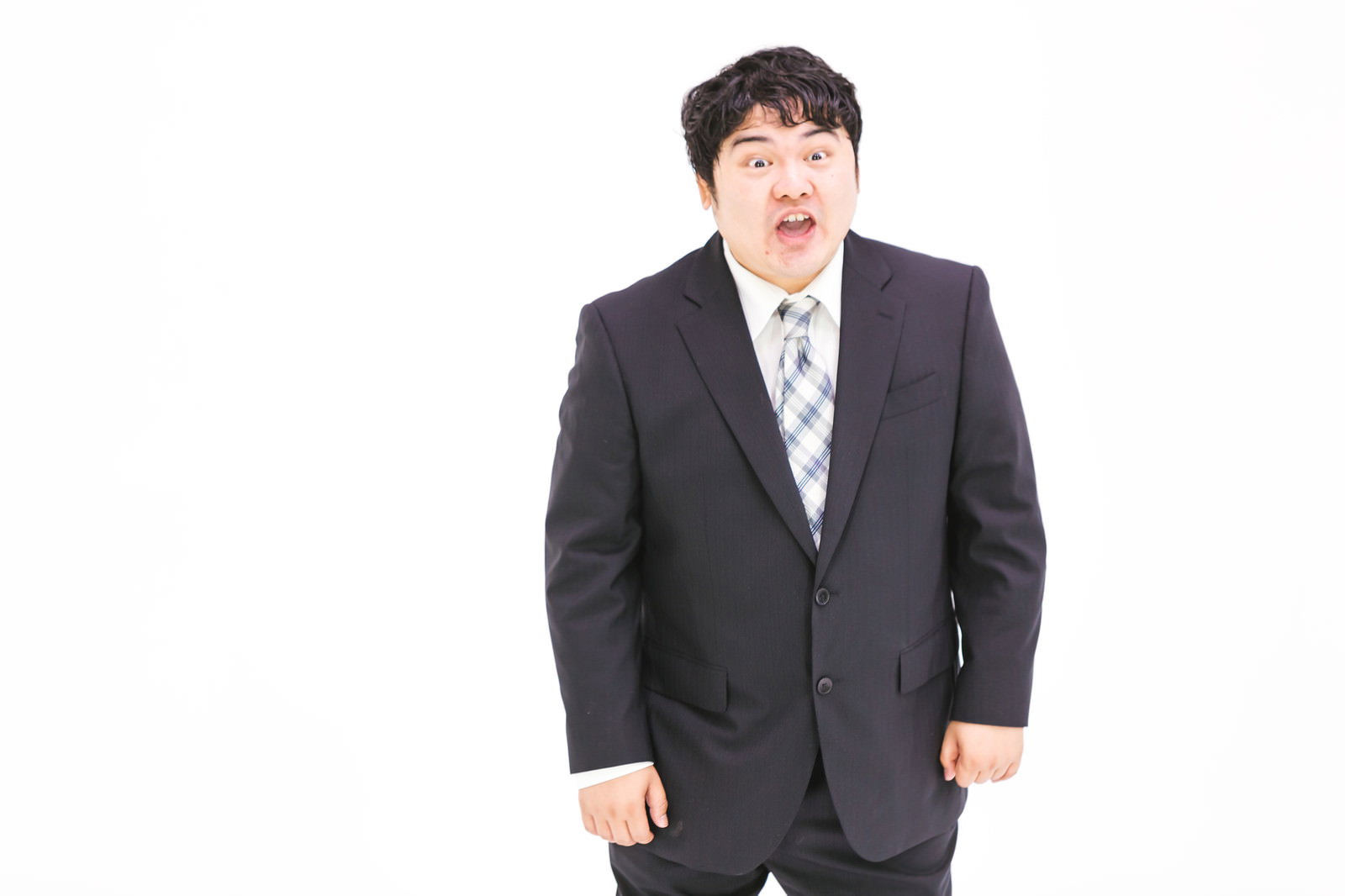 スーツを着た男性が驚いた表情で口を開けて喧嘩している様子［モデル：段田隼人］