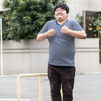 握り拳をにぎって歯を食いしばり踏ん張るメガネ男子の写真