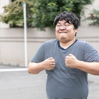 ボーダー柄のTシャツを着た喧嘩腰のメガネ男子の写真