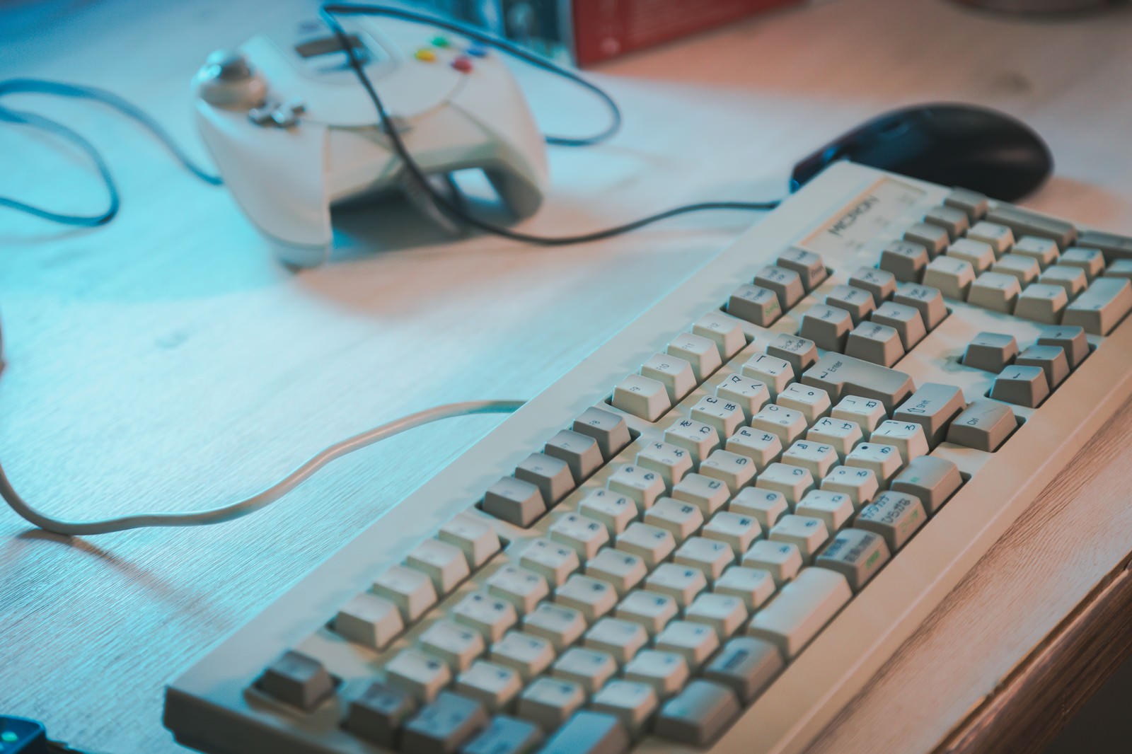 木目調のデスクに置かれた白い古いキーボードとマウス、スマートフォン