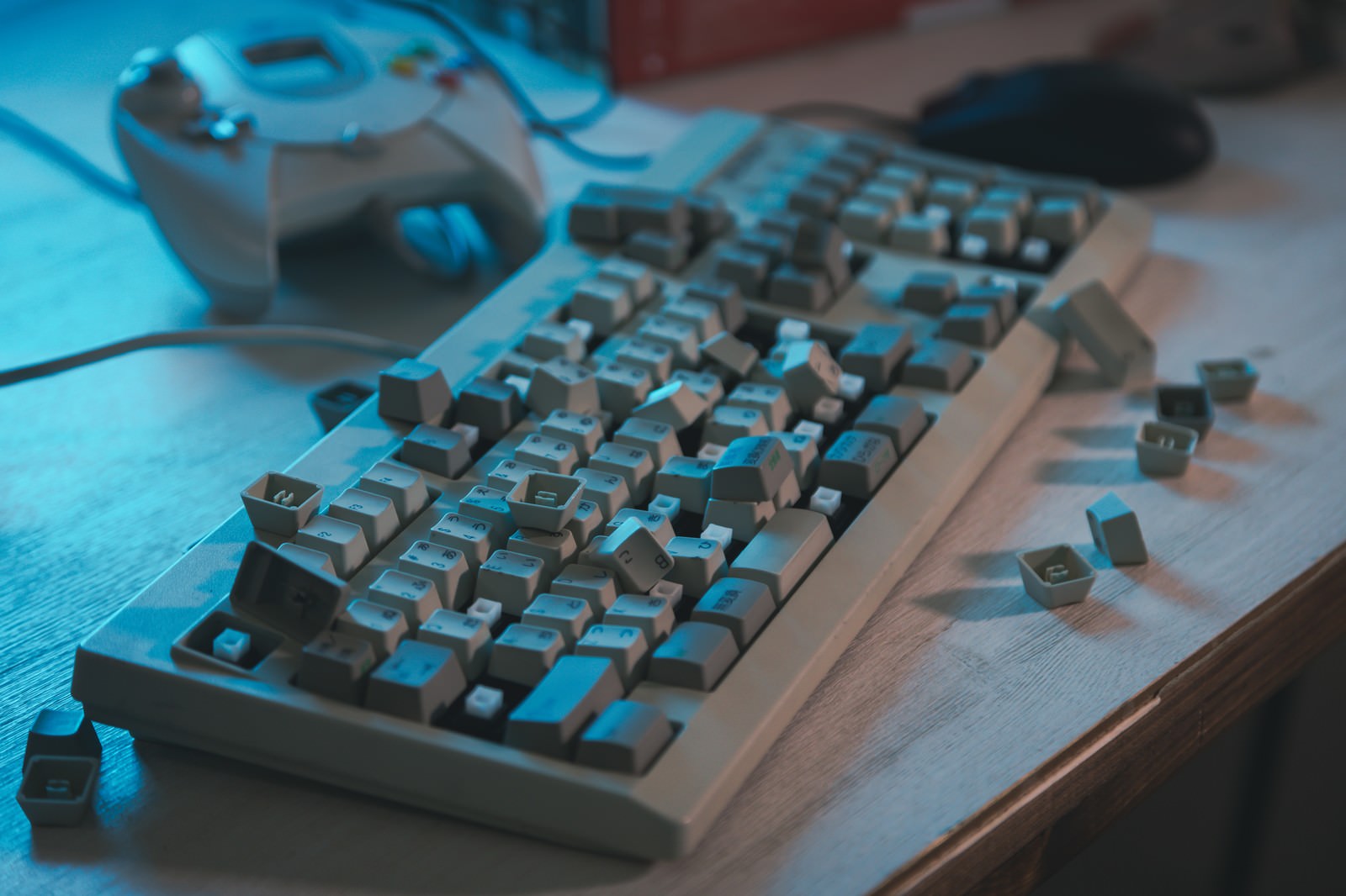 木製の机に置かれた破損したキーボードとその周りに散らばったキー