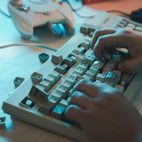 キーボードクラッシャーの手元、青い照明のもと激しくタイピングの写真