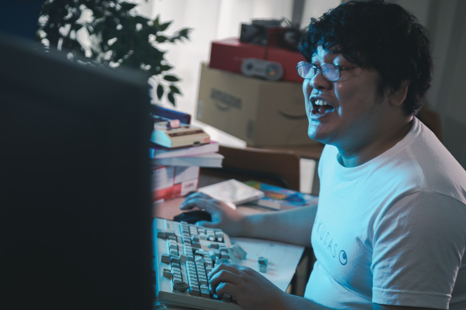 PCの前で興奮した表情を見せる男性［モデル：段田隼人］