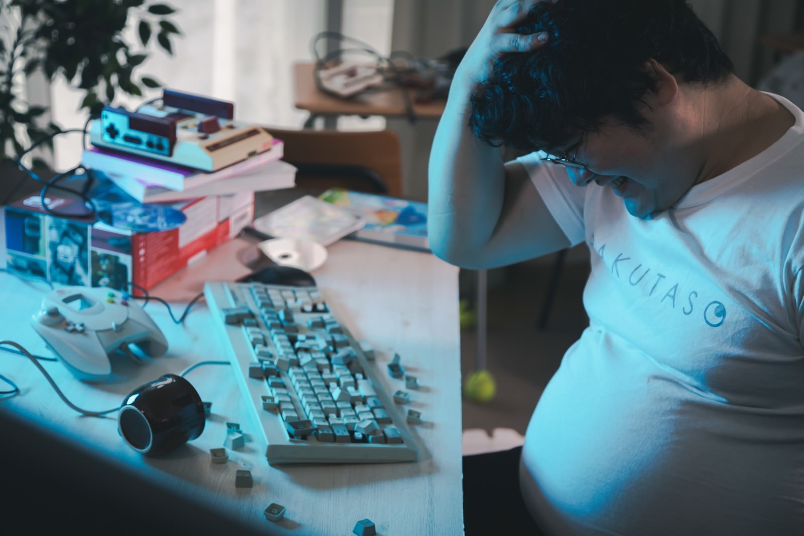デスクでキーボードを破壊して頭を抱える男性［モデル：段田隼人］
