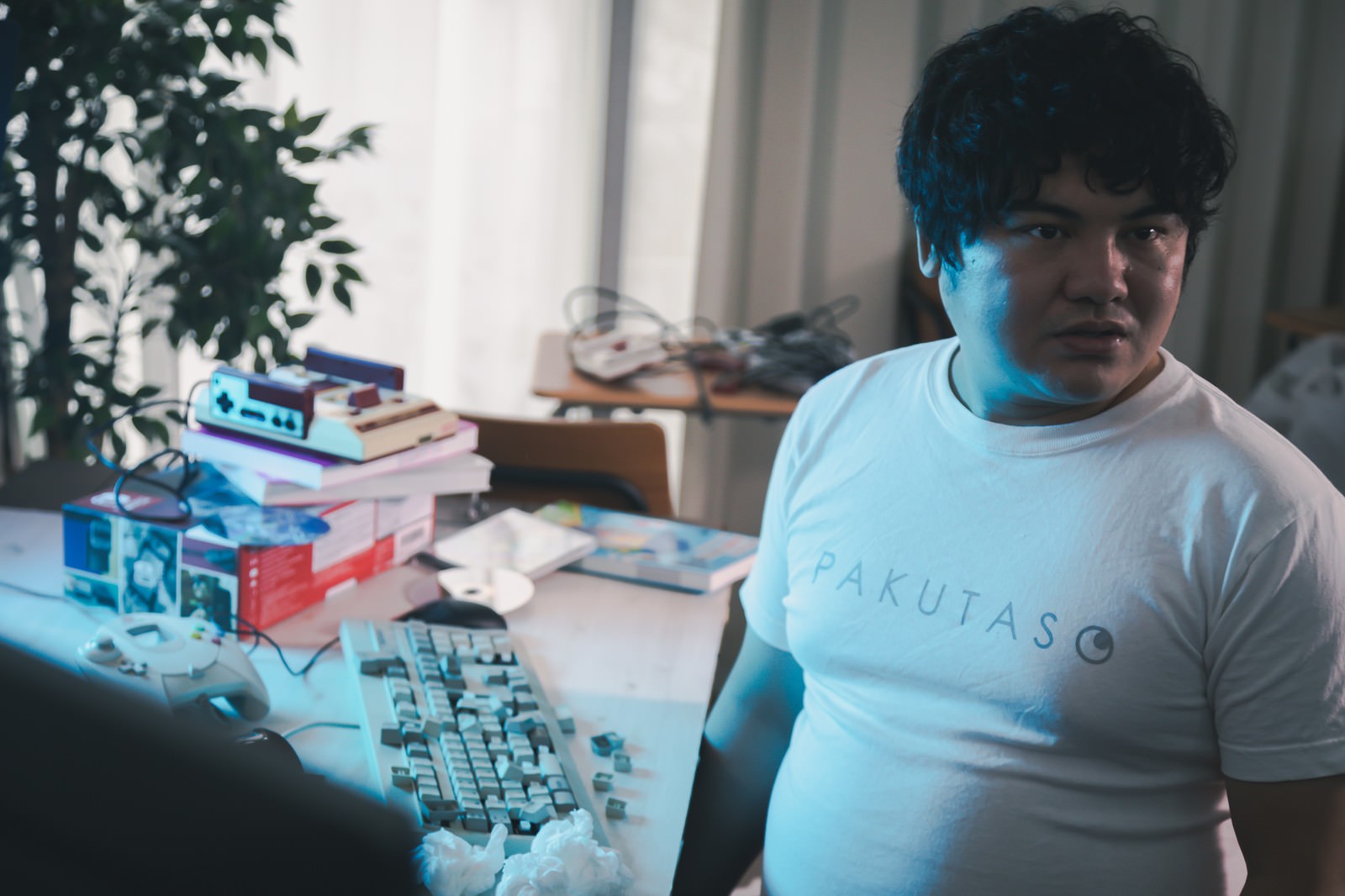 デスクでキーボードを激しく叩く白いTシャツの男性［モデル：段田隼人］