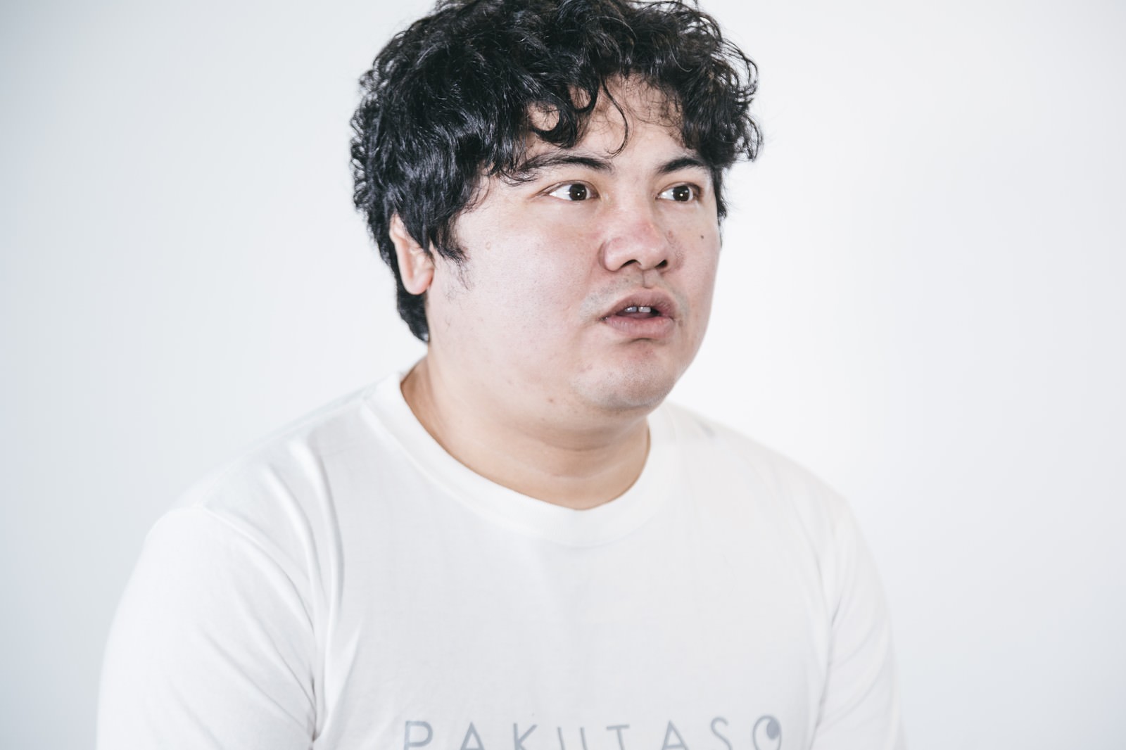 白いTシャツを着て唖然とした表情で固まっている男性［モデル：段田隼人］