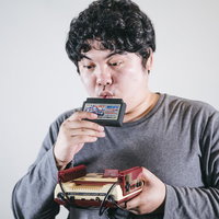 ファミコンのカセットにふぅーする男性ゲーマーの写真