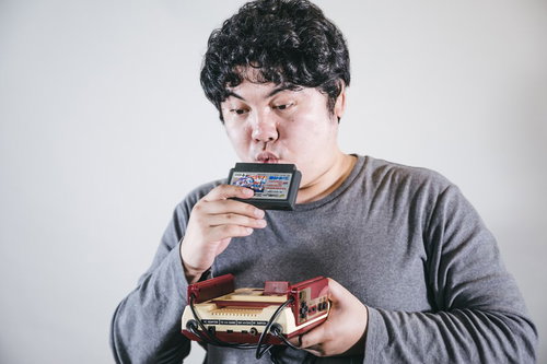 ファミコンのカセットにふぅーする男性ゲーマー