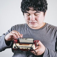 ファミコンのゲームカセットを慎重にセットする男性の写真