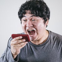 コントローラーに向かって大声を叫ぶゲーマー男性の写真