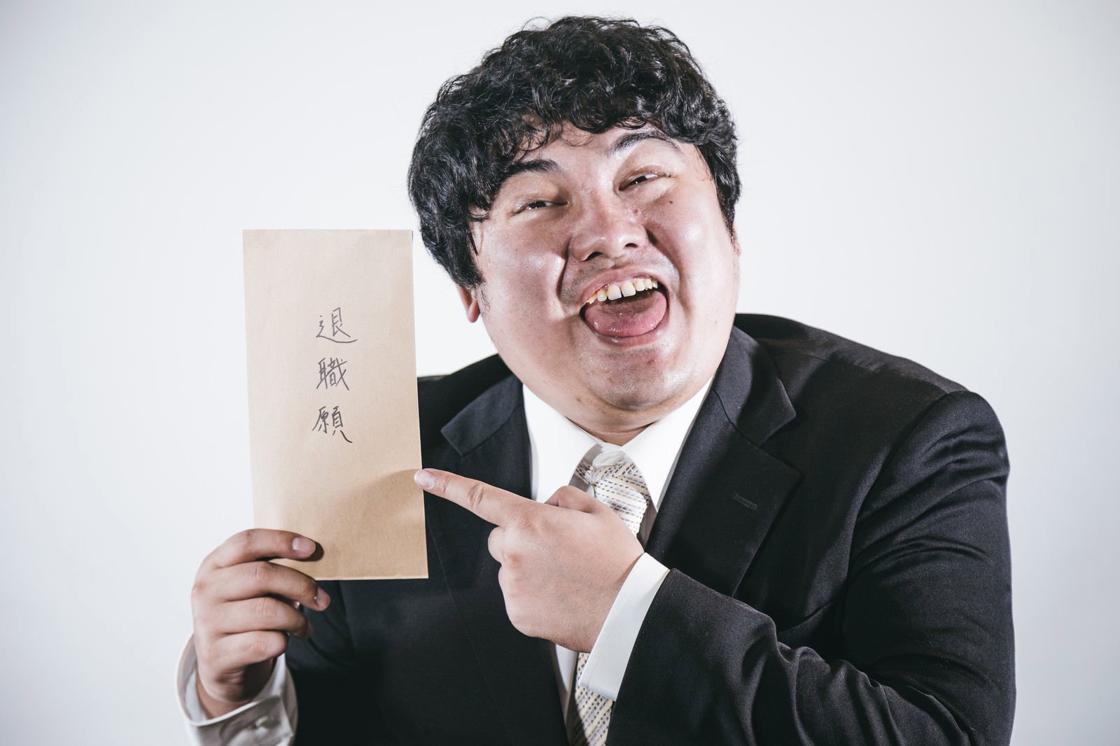 退職願を指差して笑うスーツ姿の男性［モデル：段田隼人］