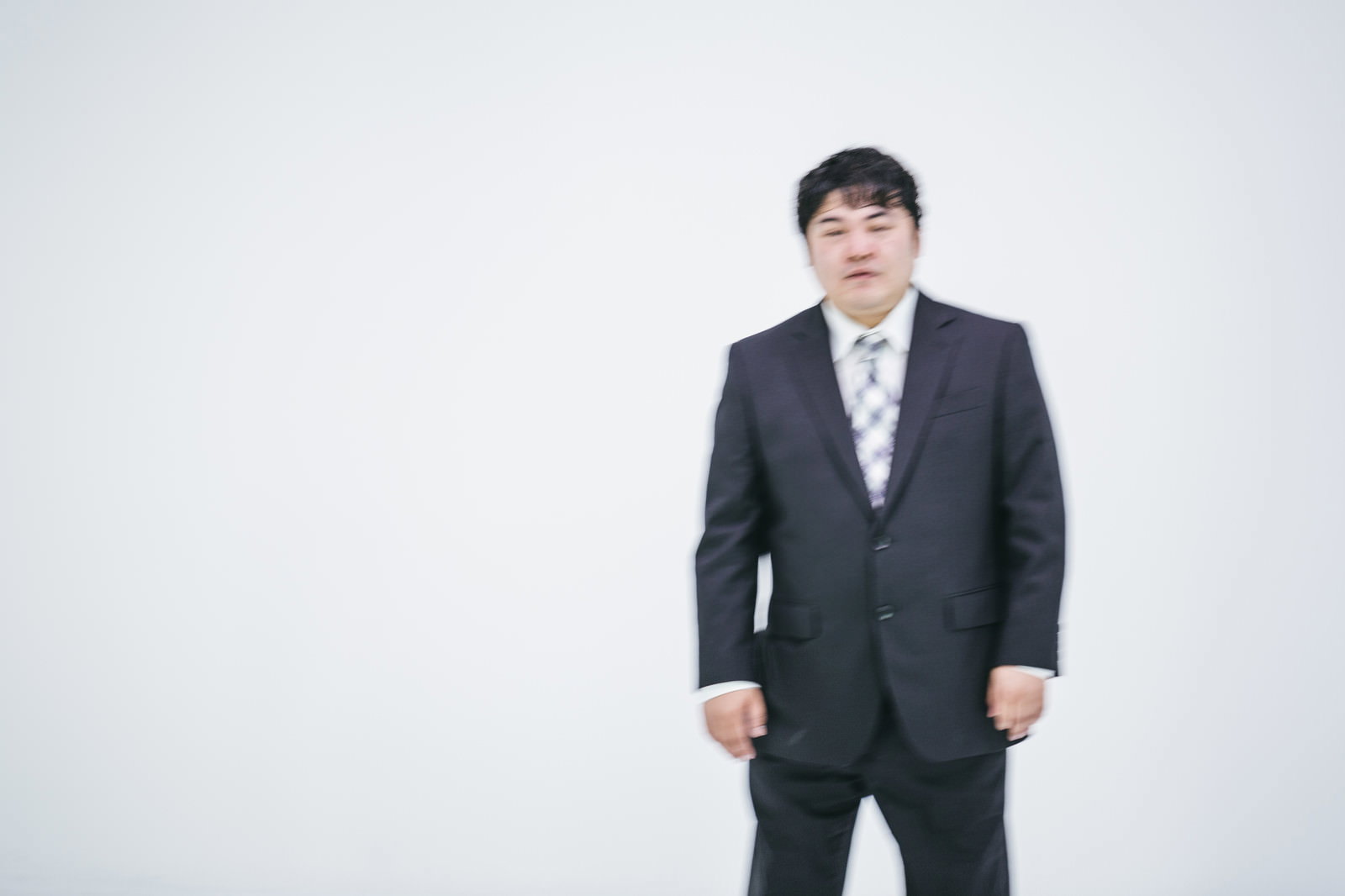 スーツ姿の男性が棒立ちで立っている［モデル：段田隼人］