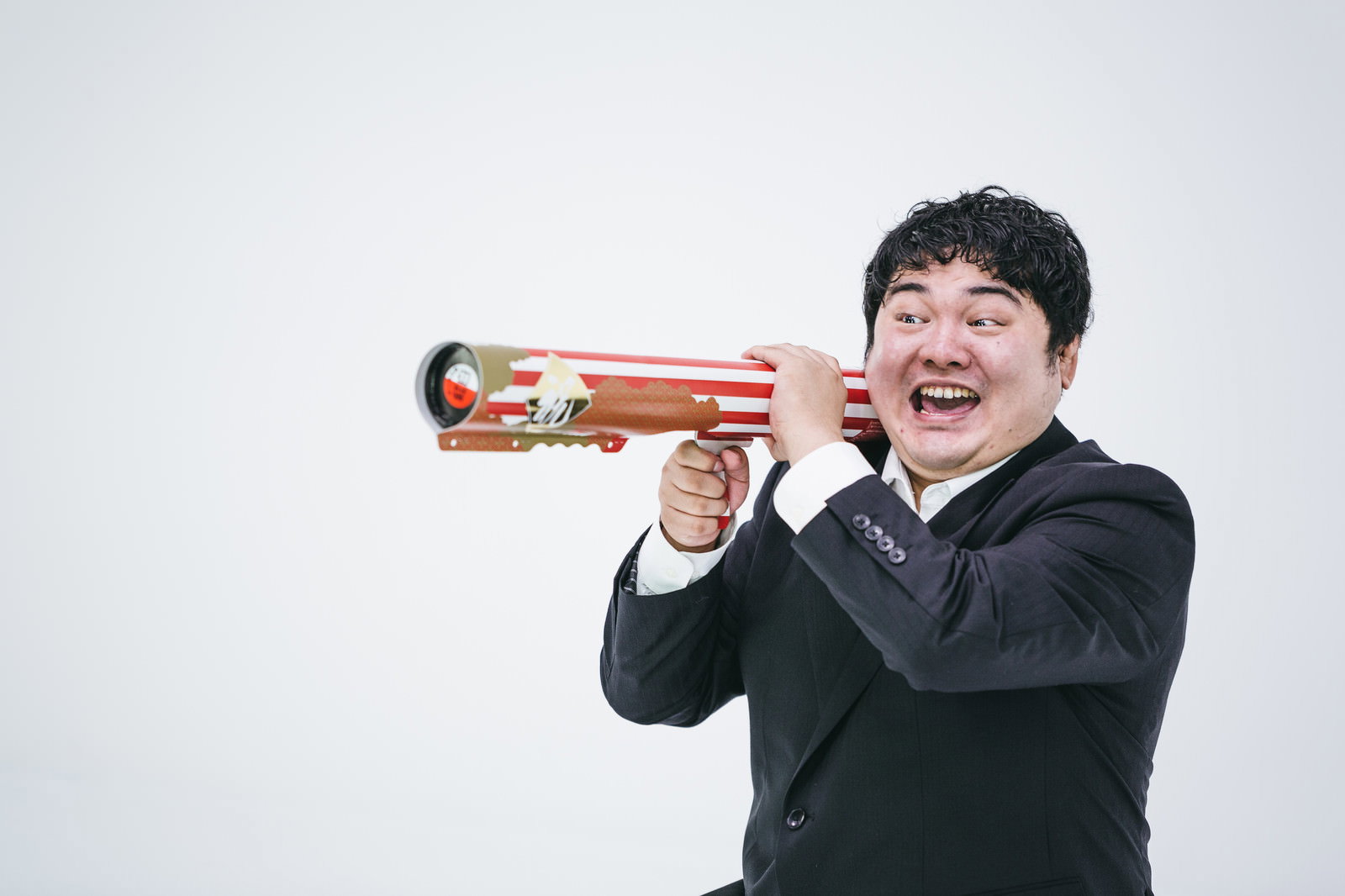 祝砲バズーカを打つスーツ姿の男性［モデル：段田隼人］
