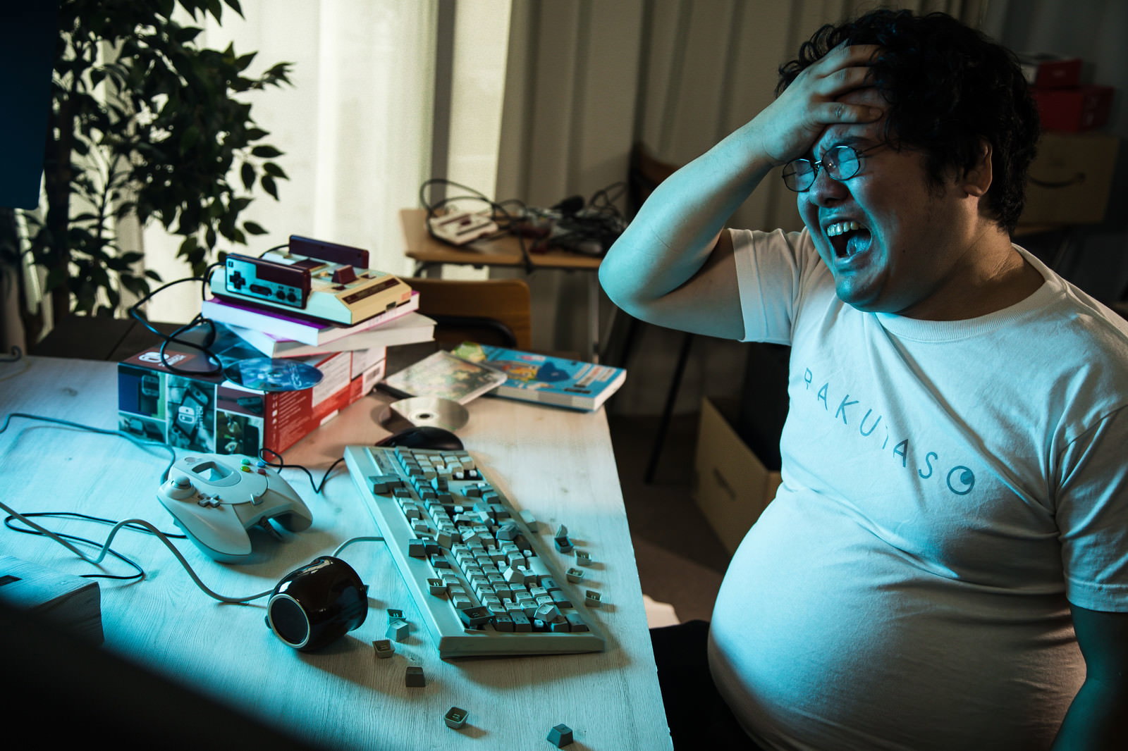 ゲームに敗北してキーボードを叩き壊し頭を抱える男性［モデル：段田隼人］
