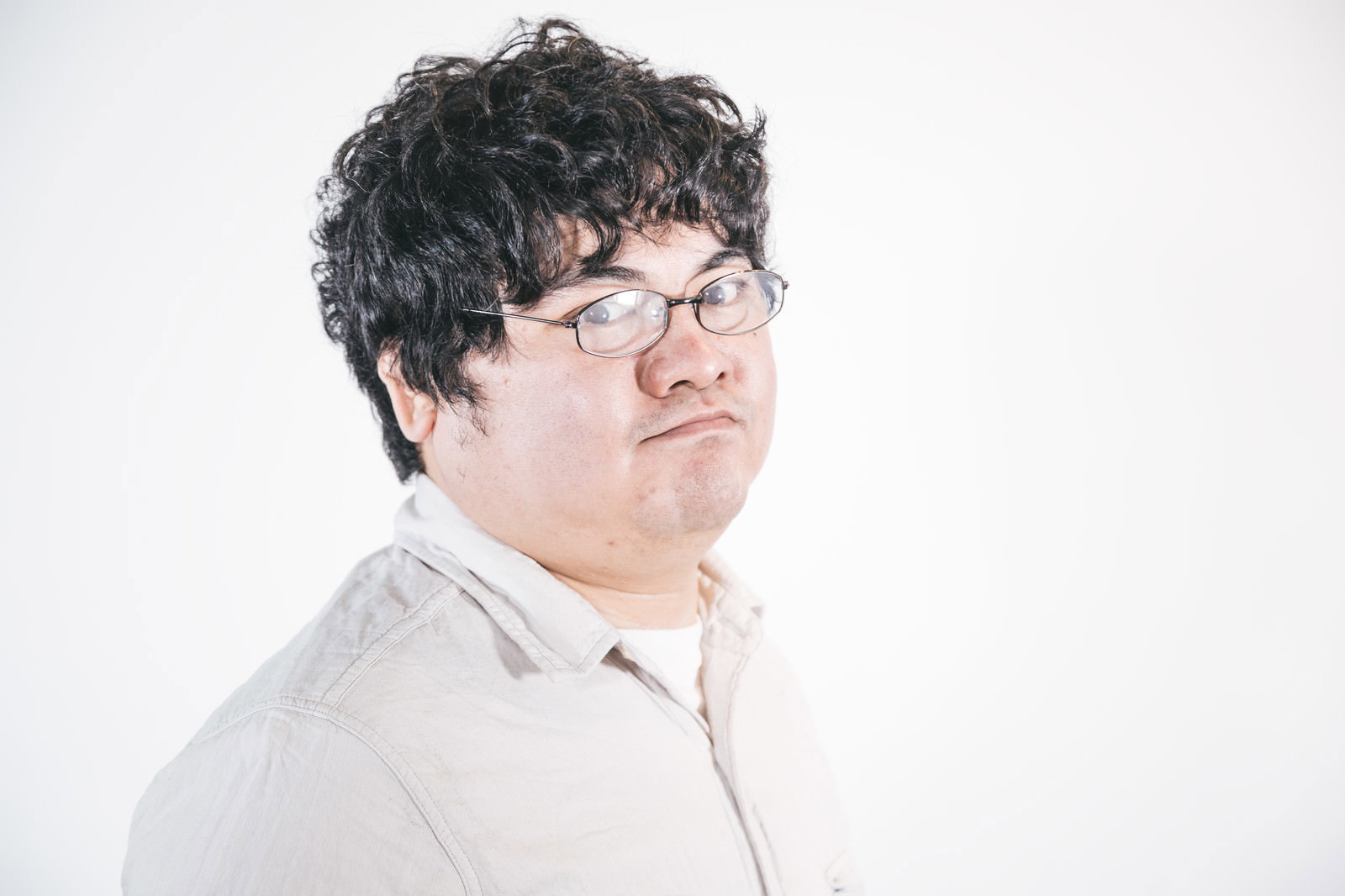 眼鏡をかけた男性が白いシャツを着てキリッとした表情で注視している［モデル：段田隼人］