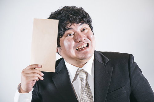 スーツ姿の男性がボーナスの茶封筒を手にして喜ぶ