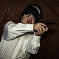 物陰に隠れて狙っているつもりが丸見え、拳銃を構える男性の写真