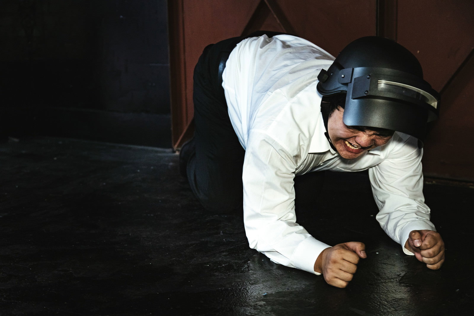 白いシャツの男性が床に四つん這いで倒れている様子［モデル：段田隼人］