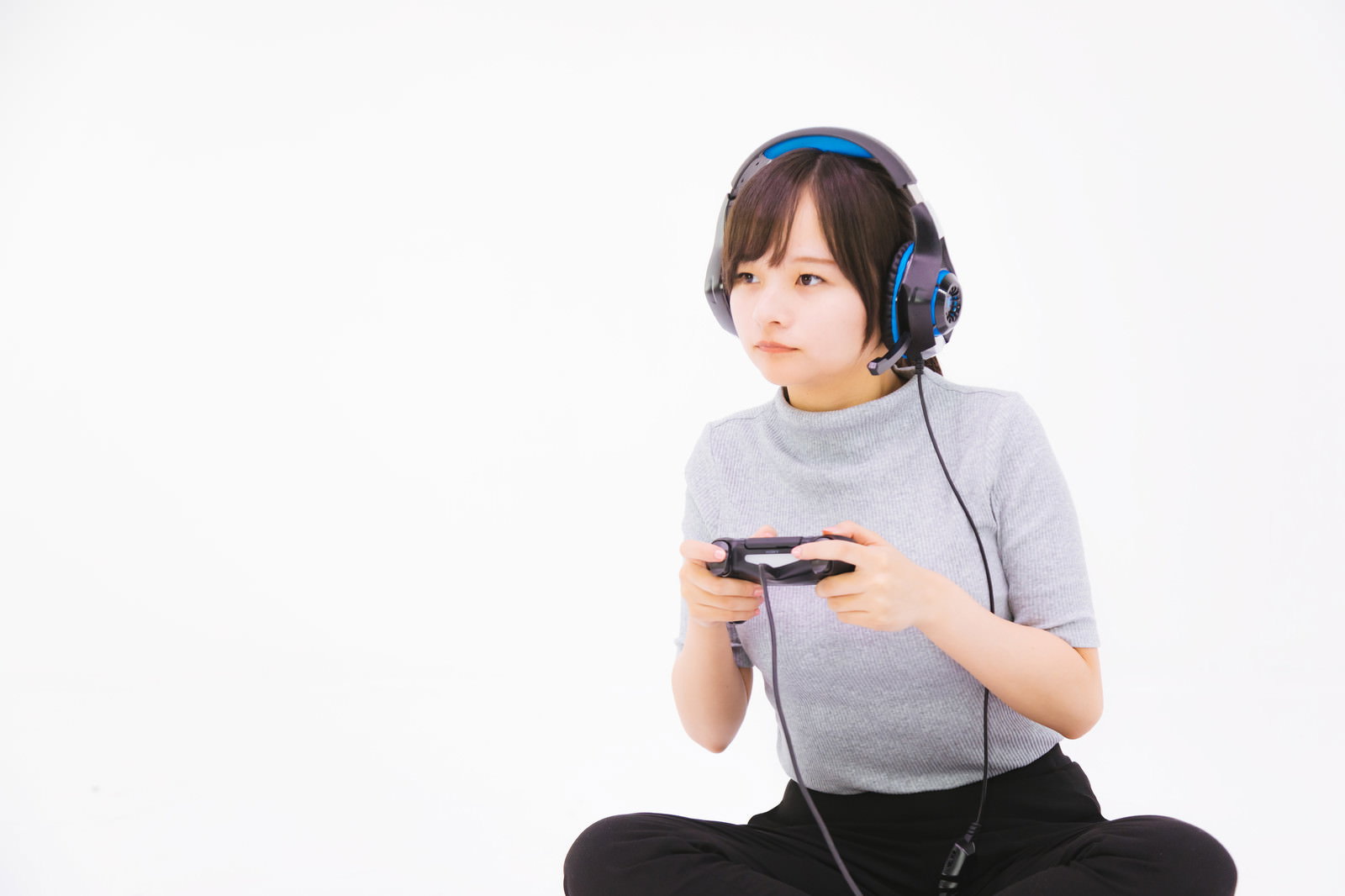 ヘッドフォンをつけてゲームコントローラーを持つ女性［モデル：千歳］