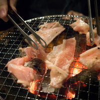 炭火焼き肉食べ放題の網上で焼く豚肉とグリル調理風景の写真