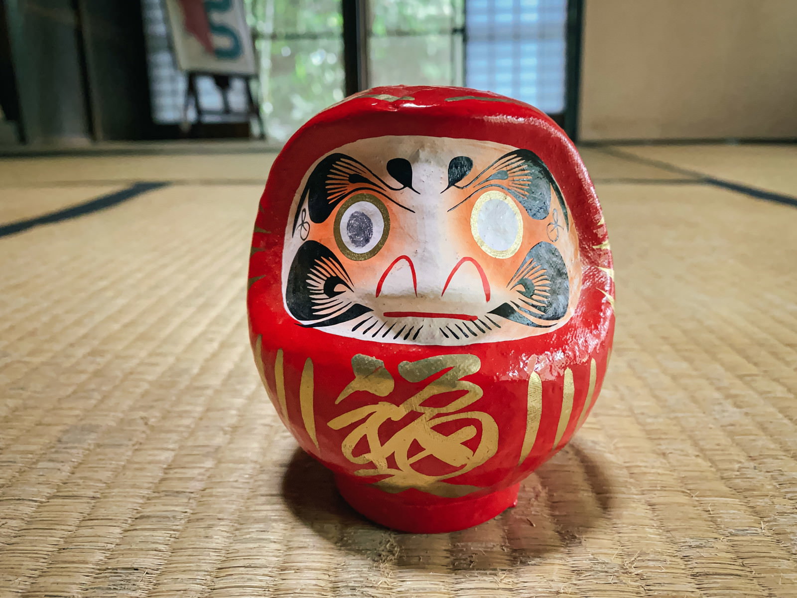畳の上に置かれた赤い達磨。片目だけが描かれている