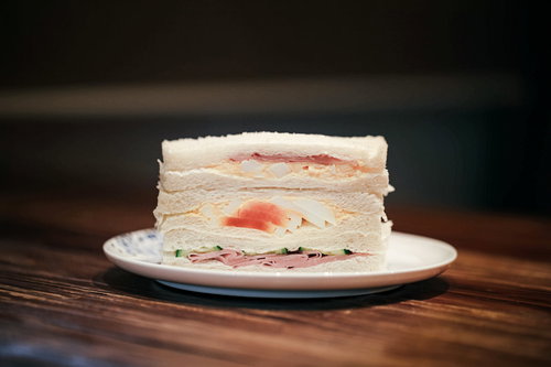 白いお皿に盛り付けたハムたまごきゅうりのサンドイッチ