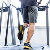 スポーツジムのランニングマシンで走る男性の写真