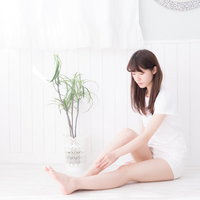 白い部屋でリラックスする美脚の女性のフットケアの写真