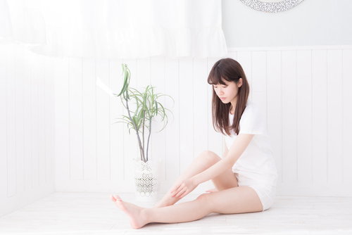 白い部屋でリラックスする美脚の女性のフットケア