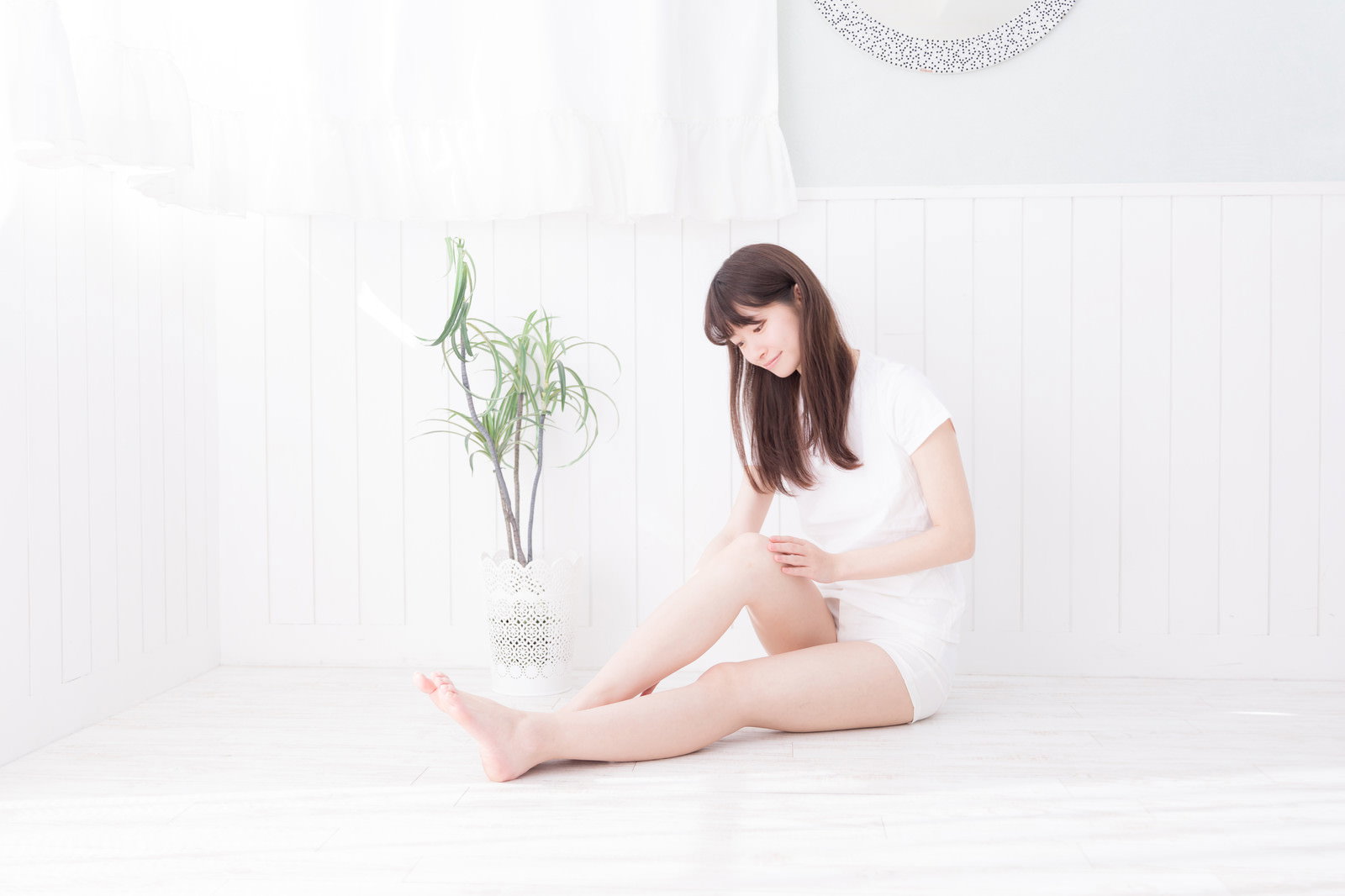床に座って脚を保湿する女性［モデル：川子芹菜］