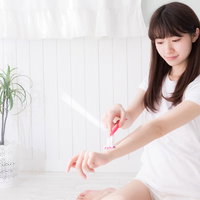 白い服姿で左腕を丁寧にセルフ脱毛する女性の写真
