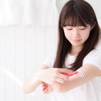 カミソリで二の腕のムダ毛を処理する女性のセルフケアの写真