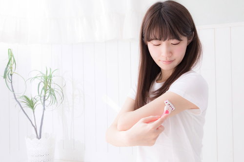左腕の裏側をカミソリで慎重に剃毛する女性