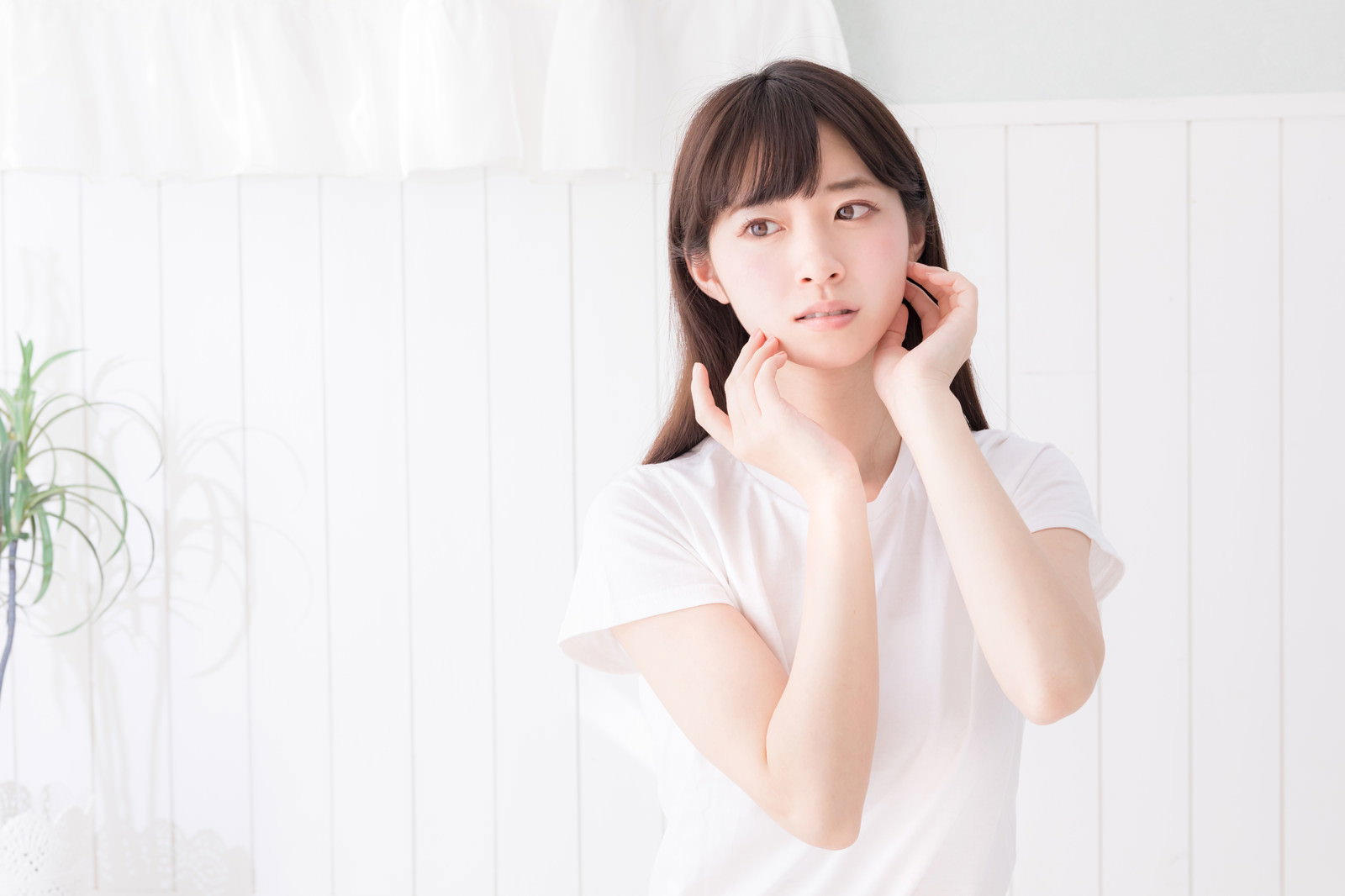 頬に手を当てて微笑む白い服の女性［モデル：川子芹菜］