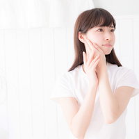 顔に手を添え遠くを見つめるスキンケアの女性の写真