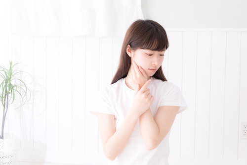 白い服を着て首元に手を添え俯く女性のスキンケア