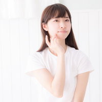 頬に指を当てて肌の弾力を確認するスキンケア中の女性の写真