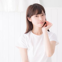 顔に手を添えてカメラ目線のスキンケア女性の写真