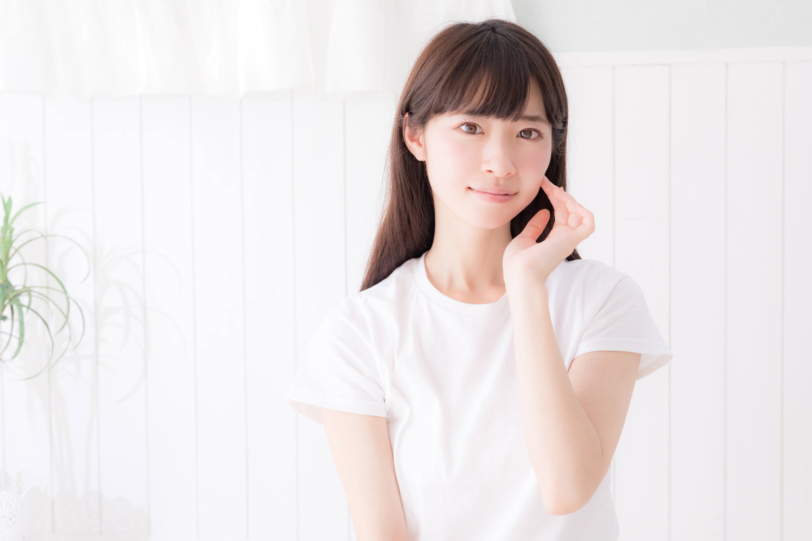 白い服を着た女性が右手を頬に当てている様子［モデル：川子芹菜］