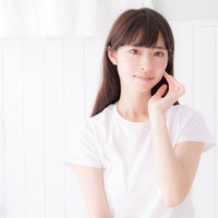 白い服を着た女性が頬の感触でスキンケア効果を確かめるの写真