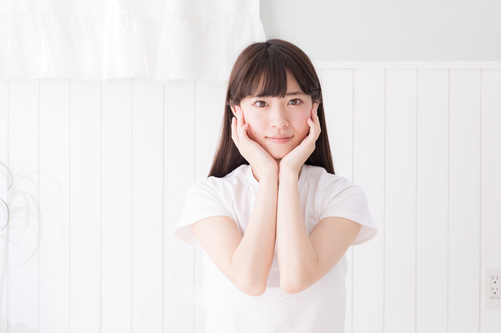 両手に顎を乗せて笑顔を見せる白い服を着た女性［モデル：川子芹菜］