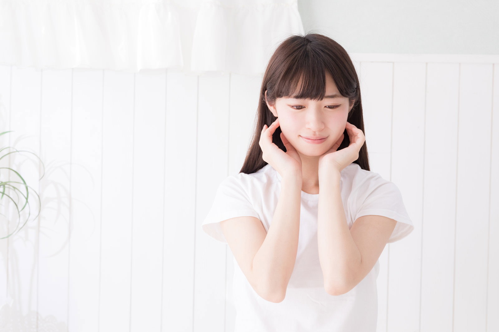 白い服を着て頬杖をつくポーズをとる透明感のある女性［モデル：川子芹菜］